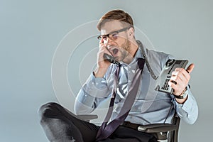 Young annoyed businessman yelling while talking on phone