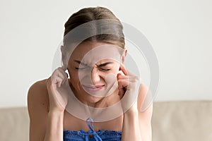 Young annoyed woman sticking fingers in ears, not listening nois photo