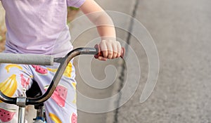 Young anonymous unrecognizable school age child riding an old used second hand bike, holding hands on handlebars closeup, detail,