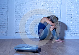 Young anorexic teenager woman sitting alone on ground looking at the scale worried and depressed in dieting and eating disorder