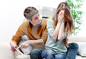 Young anxious couple quarrels by consulting their bank account