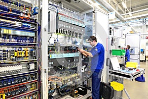 young apprentice assembles components and cables in a factory in a switch cabinet - workplace industry with future photo