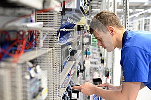 young apprentice assembles components and cables in a factory in a switch cabinet - workplace industry with future