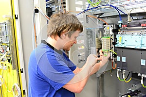 young apprentice assembles components and cables in a factory in a switch cabinet - workplace industry with future photo