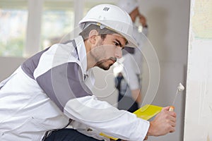 Young apprentice filling wall