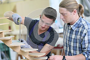 Young apprentice with instructor working on wood