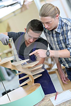 Young apprentice with instructor working on wood