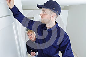 young apprentice learning how to put wallpaper up on wall