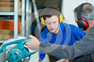 young apprentice learning to use circular saw