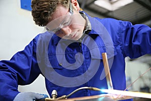 Young apprentice in plumbing working on metal