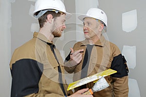 Young apprentice with professional plasterer