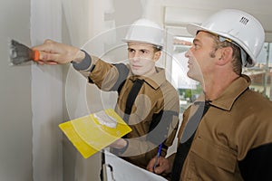 Young apprentice with professional plasterer