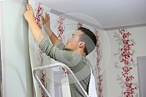Young apprentice putting wallpaper