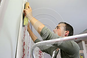 Young apprentice putting wallpaper