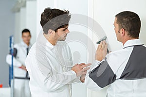 young apprentice sanding wall indoors