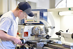Young apprentice in vocational training working on a turning machine in the industry photo