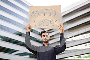 Young Arab businessman holding paper sign Need Work outdoors