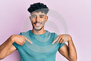 Young arab handsome man wearing casual clothes looking confident with smile on face, pointing oneself with fingers proud and happy
