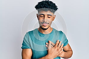 Young arab handsome man wearing casual clothes smiling with hands on chest with closed eyes and grateful gesture on face