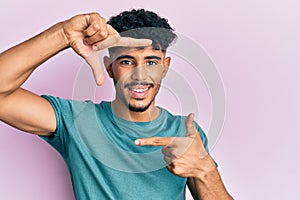 Young arab handsome man wearing casual clothes smiling making frame with hands and fingers with happy face
