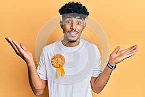 Young arab handsome man wearing fourth place badge celebrating achievement with happy smile and winner expression with raised hand