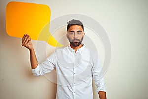 Young arab indian hispanic man holding speech bubble over isolated white background with a confident expression on smart face