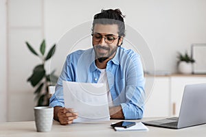 Young Arab Male Self-Entrepreneur Working With Papers At Desk In Home Office