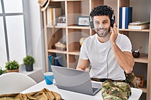 Young arab man army soldier using laptop and headphones at home