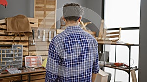 Young arab man carpenter standing backwards at carpentry