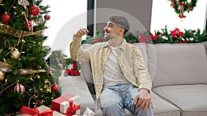 Young arab man decorating christmas tree at home