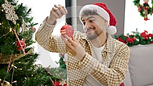 Young arab man decorating christmas tree at home