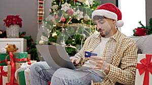 Young arab man decorating christmas tree at home