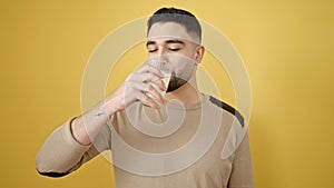 Young arab man drinking milk over isolated yellow background