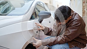 Young arab man looking crash car at street