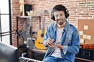 Young arab man musician composing song at music studio