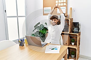 Young arab man relaxed stretching arms working at office