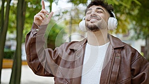 Young arab man smiling confident listening to music and dancing at park