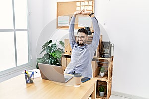 Young arab man smiling confident stretching arms working at office