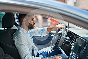 Young arab man stressed driving car at street