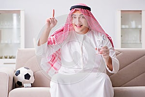 The young arab man watching football sitting on sofa