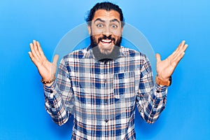 Young arab man wearing casual clothes celebrating victory with happy smile and winner expression with raised hands