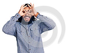 Young arab man wearing casual clothes doing ok gesture like binoculars sticking tongue out, eyes looking through fingers