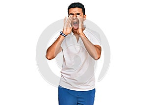 Young arab man wearing casual clothes shouting angry out loud with hands over mouth