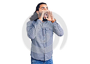 Young arab man wearing casual clothes shouting angry out loud with hands over mouth