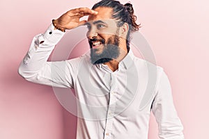 Young arab man wearing casual clothes very happy and smiling looking far away with hand over head