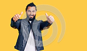 Young arab man wearing casual leather jacket approving doing positive gesture with hand, thumbs up smiling and happy for success