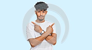 Young arab man wearing casual white t shirt pointing to both sides with fingers, different direction disagree