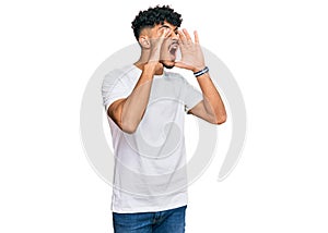 Young arab man wearing casual white t shirt shouting angry out loud with hands over mouth