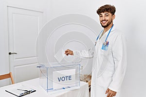 Young arab man wearing doctor uniform voting at electoral college