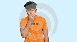 Young arab man wearing tshirt with happiness word message shocked covering mouth with hands for mistake